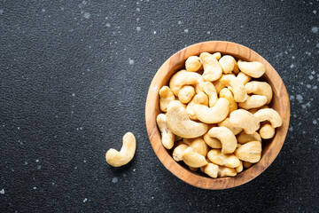 Cashew nuts in bowl at black background. Flat lay with space for text.