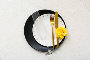 Beautiful composition with clean plates, flower, champagne glass and cutlery on white background