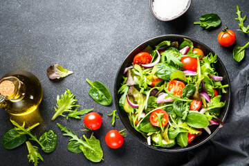 Salad, vegan food at dark background. Healthy food, diet menu. Top view.