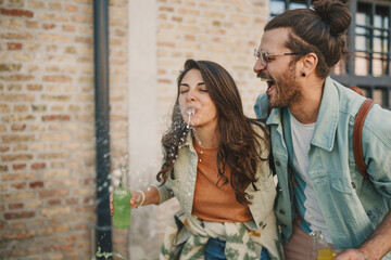 Hipster couple standing on a street and spilling juice. Copy space.