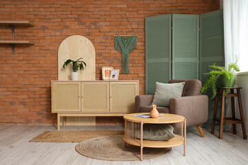 Table, chest of drawers, armchair and folding screen in interior of stylish living room