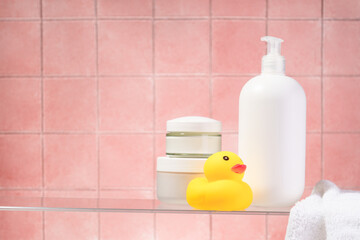 Cosmetic products at glass shelf at pink bathroom background.