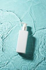 Cosmetic bottle in the water with waves. Top view.