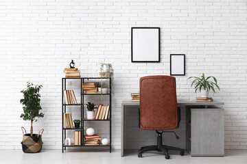 Interior of modern living room with workplace and bookshelf near white brick wall