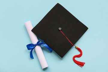 Diploma with blue ribbon and graduation hat on light blue background