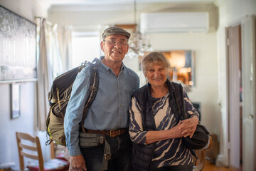 Happy active senior couple standing at home, ready for vacation travel