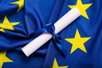 Diploma with blue ribbon on European Union flag, closeup
