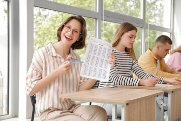 Happy female student with results of exam in classroom