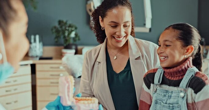 Dentist, mother and girl with model, tooth and consultation with info for oral care in clinic. Orthodontist, mom and child with advice for dental healthcare, wellness and teeth whitening in hospital