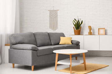 Cozy sofa with cushion and coffee table in interior of living room