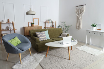 Interior of living room with cozy sofa, armchair, shelving unit and olive tree