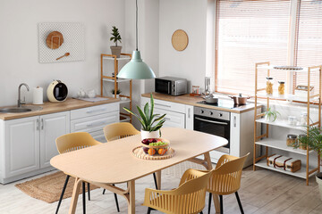 Interior of stylish kitchen with dining table, chairs and lamp