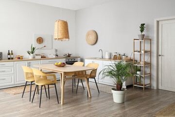 Interior of stylish kitchen with dining table, chairs, white counters and lamp
