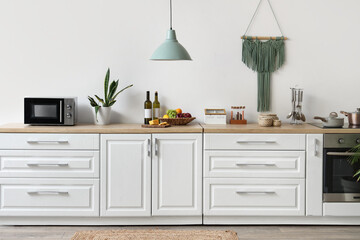 Interior of beautiful kitchen with white counters, lamp and microwave