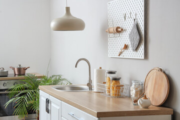 Interior of beautiful kitchen with white counters, sink and lamp