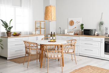 Interior of beautiful kitchen with white counters, dining table, chairs and lamp