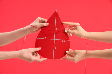 people holding paper drop with tube on red background. Blood donation concept