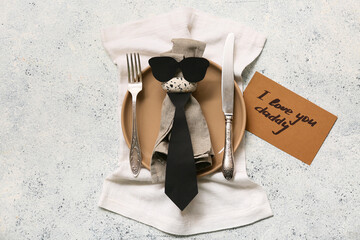 Stylish table setting with greeting card and tie on white grunge background. Father day celebration...