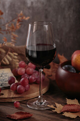 Glass of red wine served with blue cheese on dark wooden background. Autumn picnic with wine and...