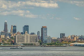 New York, NY, USA - August 1, 2023: Bridge Park drive building and NYU Langone health center in Brooklyn along east river mouth under blue cloudscape