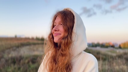 young cute woman dreaming and praying outdoors at sunset or sunrise in the park