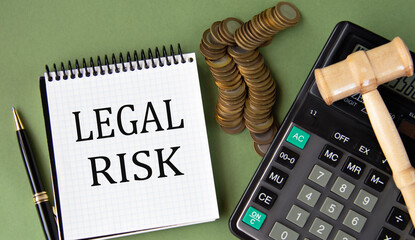 LEGAL RISK - words in a notepad against the background of a calculator and a judge's gavel