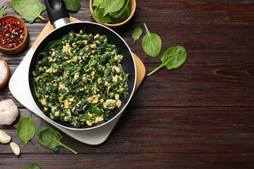 Tasty spinach dip with eggs in dish served on wooden table, flat lay. Space for text