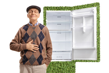 Satisfied senior holding his hand on his stomach in front of a green efficient fridge