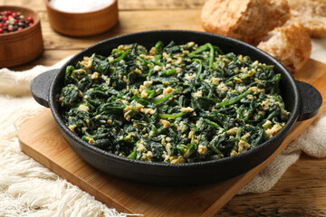 Tasty spinach dip with eggs in dish served on wooden table, closeup