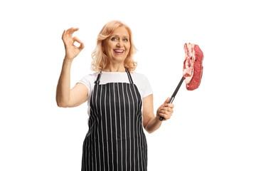 Woman holding a raw meat steak on a fork and gesturing ok sign