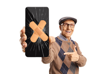 Senior man holding a mobile phone with cracked screen fixed with a tape and pointing