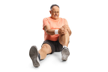Mature man sitting on the floor and holding his injured knee