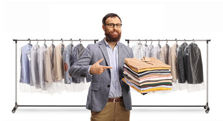 Man pointing at a pile of folded clothes in front of a rack with clothes on hangers