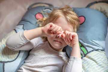 Little Girl Laying on Bed With Hands on Face
