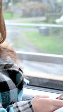 train window mobile phone hands of young girl riding in carriage travel mobile network wi-fi autumn spring warm plaid jacket White phone case listen to music look for news. Correspond