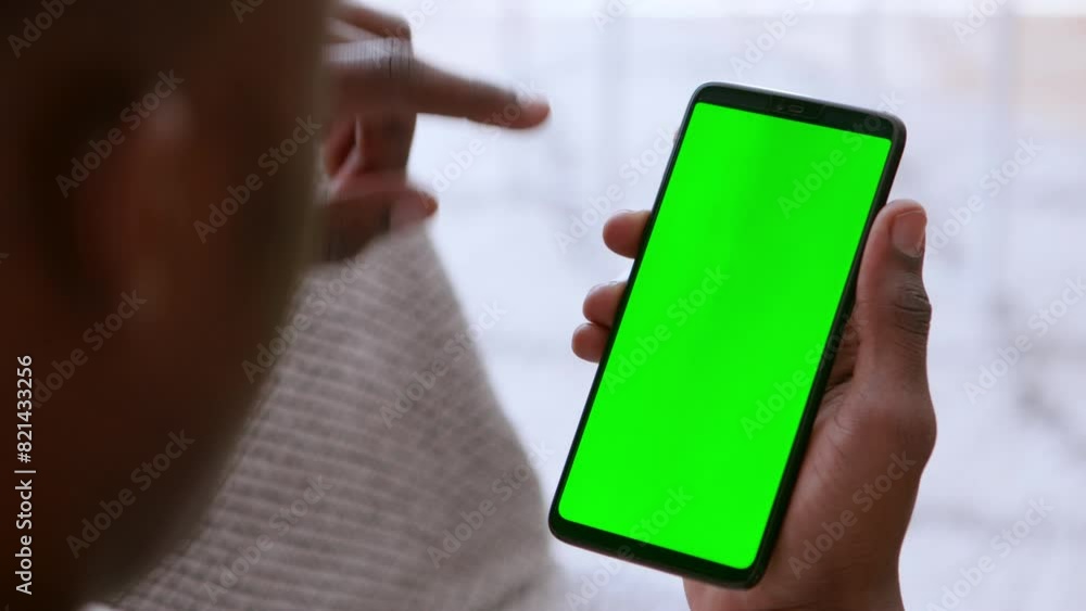 Poster african man browsing on cellphone, scrolling on green chroma key device screen, close up