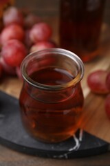 Wine vinegar in glass jar and grapes on table, closeup