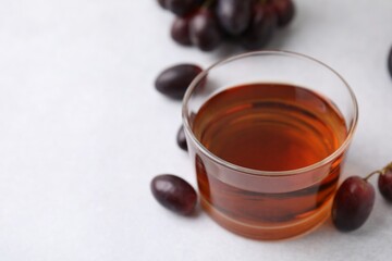 Wine vinegar in glass bowl and grapes on light grey table, closeup. Space for text