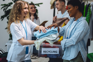 Concept of textile pollution, conscious consumption. Ecology, sustainable lifestyle. Group of volunteers, young women, sorting clothes in charitable foundation for charity donation, recycling.