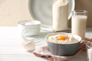 Making dough. Flour with yolk in bowl on white wooden table, closeup