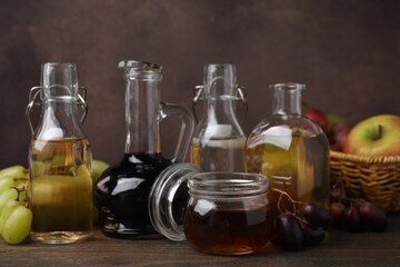 Different types of vinegar and fresh fruits on wooden table