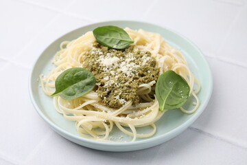 Tasty pasta with spinach, cheese and sauce on white tiled table