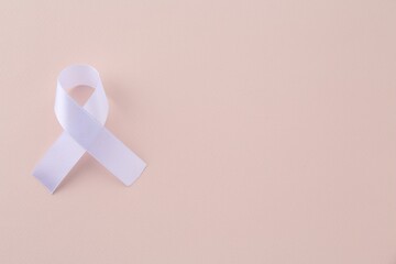White awareness ribbon on beige background, top view. Space for text