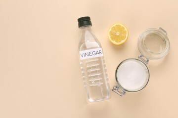 Eco friendly natural cleaners. Vinegar in bottle, cut lemon and jar of soda on beige background,...