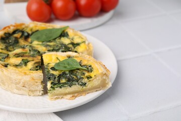 Delicious pie with spinach on white tiled table, closeup. Space for text