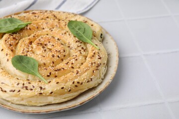Delicious puff pastry with spinach on white tiled table, closeup