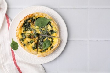 Delicious pie with spinach on white tiled table, top view. Space for text