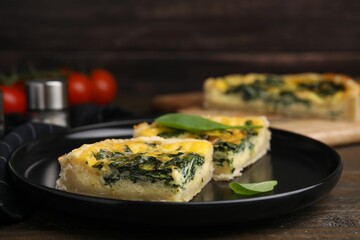 Pieces of delicious pie with spinach on wooden table, closeup