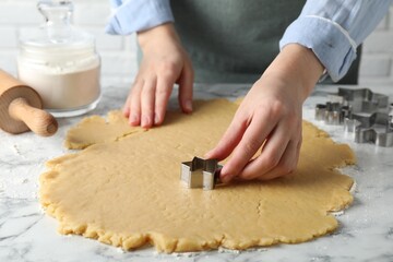 Shortcrust pastry. Woman making cookies with cutter at white marble table, closeup