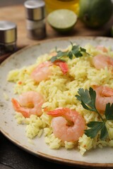 Delicious risotto with shrimps and parsley on wooden table, closeup